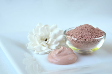 Deep cleansing cosmetic bentonite (montmorillonite) clay for beauty spa face mask, body detox and hair treatments. Clay and activated charcoal powder and mask in glass bowl.
