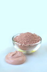 Deep cleansing cosmetic bentonite (montmorillonite) clay for beauty spa face mask, body detox and hair treatments. Clay and activated charcoal powder and mask in glass bowl.
