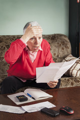 Senior old woman shocked with the bills she receives, appalled and gasping