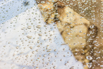 Rain drops on glass reflecting the sky and the house
