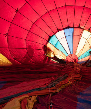 Two People Checking a Hot Air Balloon while it's being inflated.