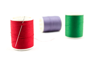 Spool of green thread and needle on white background