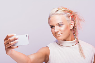 Gorgeous young woman taking a selfie or filming a vlog using smartphone, wearing makeup and and...