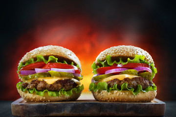 Pair of delicious burgers on fire background