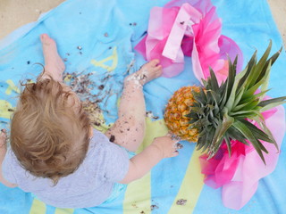 messy baby on a towel with pineapple at the beach 