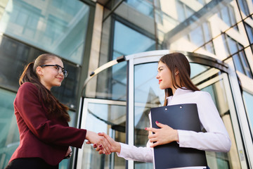 two girls managers smile and shake hands after signing a contract or a successful deal