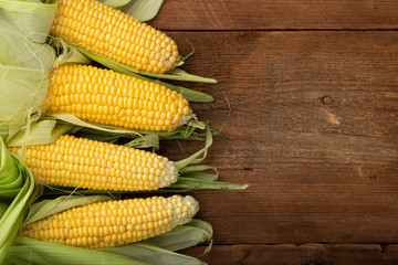 Fresh corn on cobs on rustic wooden table, closeup. Top view with copy space
