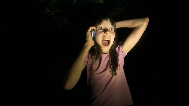frightened little girl, screaming and calling for help, trying to get through the phone to parents. the child was lost at night in the forest
