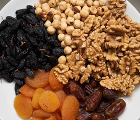 Mix of dry nuts and fruits. Composition with dried fruits and assorted nuts on white plates, top view
