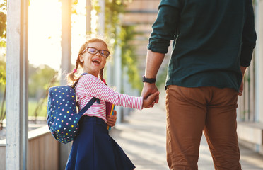 first day at school. father leads  little child school girl in first grade