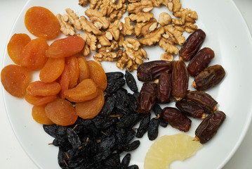 Mix of dry nuts and fruits. Composition with dried fruits and assorted nuts on white plates, top view