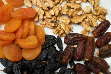 Mix of dry nuts and fruits. Composition with dried fruits and assorted nuts on white plates, top view