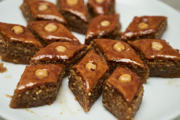 Traditional Azerbaijan dessert baklava with walnuts and cardamom on white plate. Homemade baklava with nuts and honey.