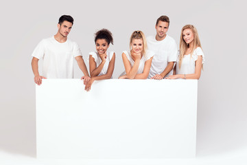 Group of smiling people with empty white board.