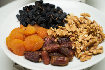 Mix of dry nuts and fruits. Composition with dried fruits and assorted nuts on white plates, top view
