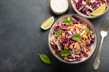 Purple cabbage and carrot salad with mayonnaise in a white bowl on a black background. Classic coleslaw. Diet vegetarian dish. Top view with copy space