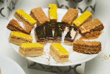 Slices of cakes served on a white plate, close-up. Sweets, desserts at buffet breakfast
