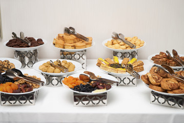 Mix of dry nuts, fruits and biscuits dessert . Composition with dried fruits and assorted nuts and sweets cookies on white plates at restaurant buffet breakfast table