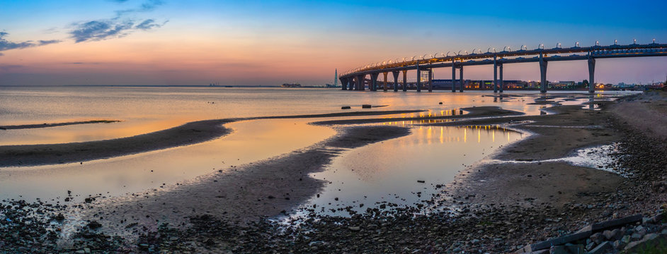 Panorama of the outskirts of the city. Low tide. Sunset on the background of the city. Panorama of the shore in the city.