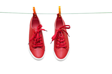 Red sneakers hang on clothespins on a rope. Close-up.