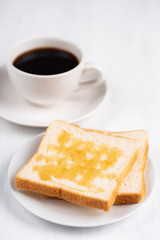Sliced bread with honey topping and cup of black coffee on white table, delicious breakfast