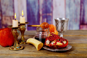 Honey, apple and pomegranate on wooden table over bokeh background © ungvar