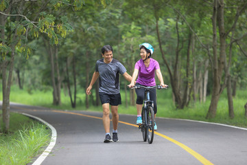 Middle aged couple walking with their bicycle in park