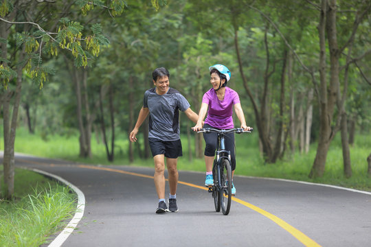 Middle aged couple walking with their bicycle in park
