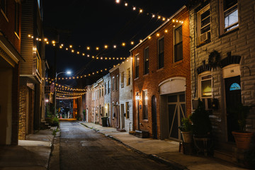 Fototapeta na wymiar String lights over Chapel Street at night in Butchers Hill, Baltimore, Maryland