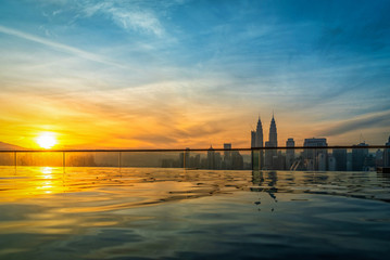 Cityscape of Kuala lumpur city skyline with swimming pool on the roof top of hotel at sunrise in Malaysia.