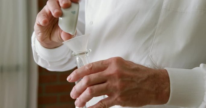 vintage pharmacist adding a powder from a mortar and pestle and liquid to a bottle