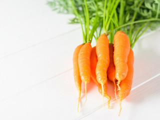 Bunch of fresh carrots on a white wooden table.