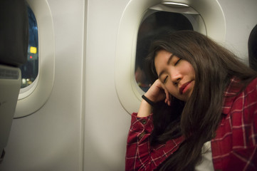 lifestyle portrait of young beautiful and sweet Asian Korean tourist woman sleeping on plane during long flight feeling tired taking a nap in holidays travel