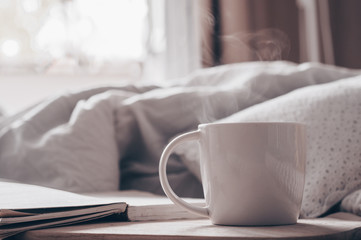 Breakfast in bed, a tray of tea, croissants, fruit, flowers. Open the book the text is out of focus. Background layout. a day off