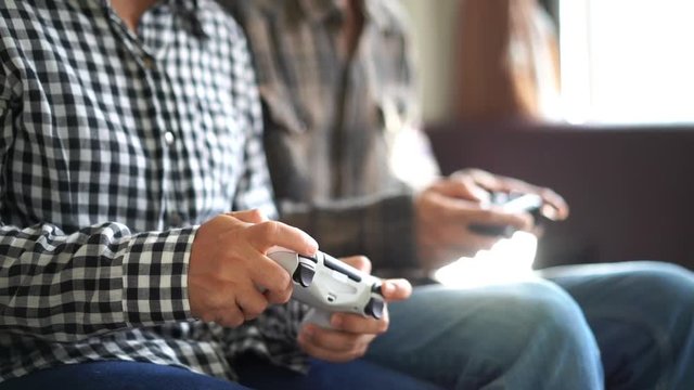 Closeup view of Male and female hands playing video game at home. Shooting and controlling using the game controller. Wireless game controller