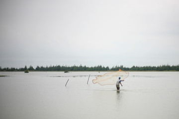 Fototapeta na wymiar Fisherman Fishing with a fishing net on the beach in Cox's Bazar Bangladesh during sunset
