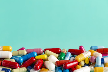 Color capsules and pills on blue background, top view copy space