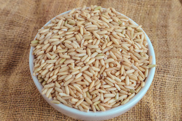 Raw brown rice in a bowl. top view food background