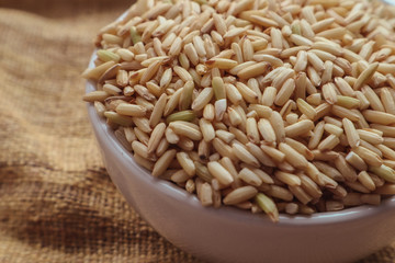 Raw brown rice in a bowl. top view food background