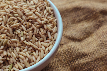 Raw brown rice in a bowl. top view food background