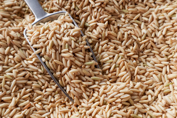 Raw brown rice in a spoon and bowl. top view food background