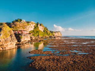 Aerial view of cliff, rocks and ocean at low tide in Bali