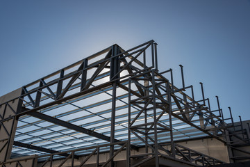 The steel framework of a prefabricated warehouse building against the sun and blue sky