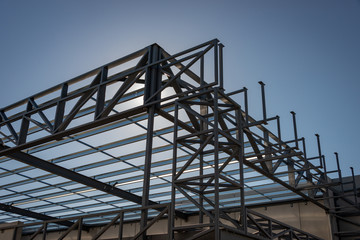 The steel framework of a prefabricated warehouse building against the sun and blue sky