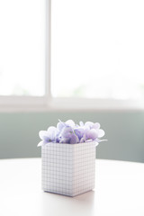 close up of small violet artificial trees in a pot on a white table.
