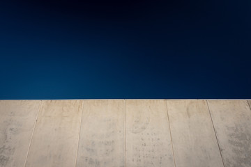 A wall of prefabricated concrete against a dark blue sky with open negative space