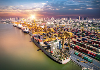 Naklejka premium Logistics and transportation of Container Cargo ship and Cargo plane with working crane bridge in shipyard at sunrise, logistic import export and transport industry background