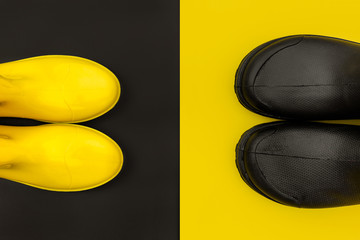 Black and yellow rubber boots on yellow and black backgrounds. The view from the top. Bright and contrast the concept of autumn.