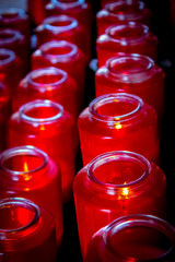 Beautiful bright red glass prayer candles lined up in rows.
