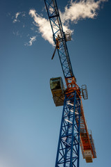 Construction crane partially silhouetted against a blue sky and bright cloud